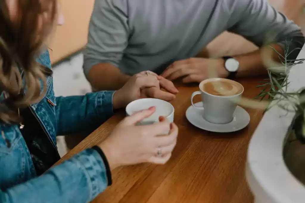 A photo of a woman's hand holding a small cup of coffee.